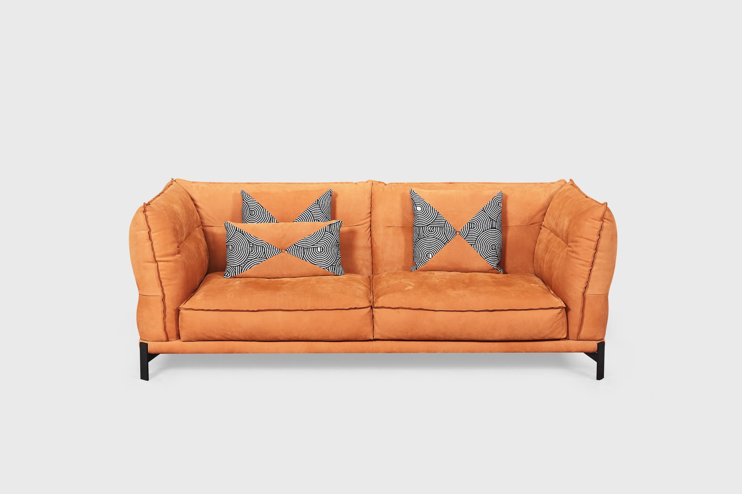 Gota burnt amber three seater sofa with plump outward-stitched cushion edges and black runner legs
